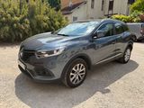 La voiture grise est garée sur le parking à côté d'une maison.