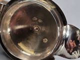 a close up of a silver teapot on a table