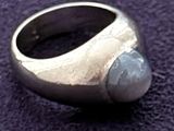 a silver ring with a stone in it on a purple surface