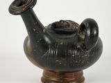 a black vase with a face on it on a stand