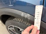 a person holding a ruler in front of a car