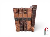 several old books are stacked on top of each other on a white surface