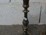 pair of antique brass candlesticks on concrete floor with brick wall in background