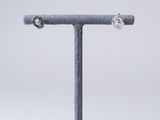 pair of silver earrings on a stand against a white background