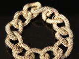 a close up of a gold chain bracelet on a black surface