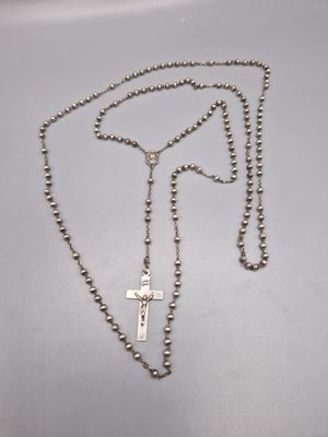 un collier de chapelet avec une croix suspendue à une chaîne, posé sur une table