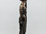 a bronze statue of a woman holding a lamp on top of a table