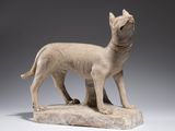 statue d'un chien debout sur un rocher, sur fond gris