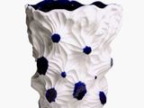 un vase blanc contenant des fleurs bleues, posé sur une surface blanche