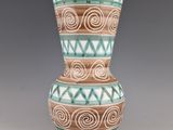 a green and brown vase with spiral designs on it