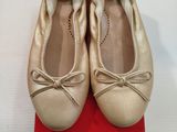 une paire de ballerines beiges posée sur une boîte rouge