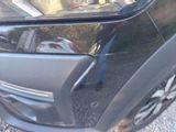 a close up of a car ' s front bumper with a reflection of a person in the window
