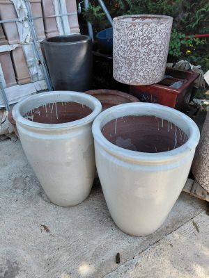two large pots sitting next to each other on the sidewalk