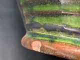a close up of a green and brown vase on a table
