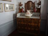 une commode sur laquelle est posé un bol, dans une pièce où il y a des tableaux accrochés au mur
