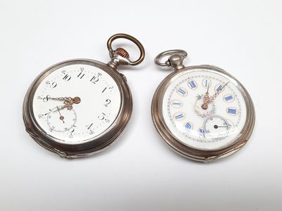 deux montres de poche en argent posées l'une à côté de l'autre sur une surface blanche