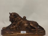 a bronze statue of a lion laying down on a rock