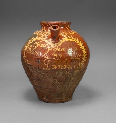 a brown vase with writing on it sitting on a table