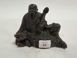 une image représentant la statue d'un homme assis sur un rocher