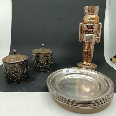 une assiette en argent sur laquelle est posé un casse-noisettes, à côté d'un bol en argent et d'une assiette en argent sur laquelle est posé un casse-noisettes