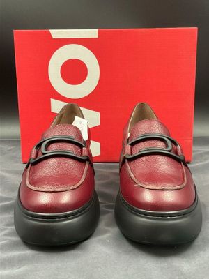 une paire de chaussures rouges à semelles noires posée sur une boîte rouge