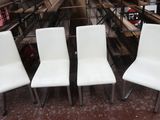trois fauteuils en cuir blanc placés dans une pièce où se trouvent de nombreuses étagères