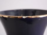 a blue vase with a gold rim sitting on a table