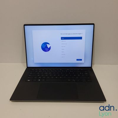 un ordinateur portable ouvert posé sur une table blanche
