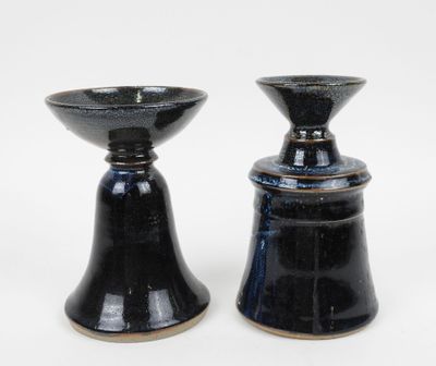 deux vases noirs posés l'un à côté de l'autre sur une surface blanche