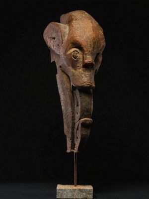 a carved head of an elephant on a wooden stand