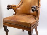 une image représentant un fauteuil en cuir marron dont l'accoudoir est orné d'une tête de lion