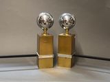 two golden trophies sitting on top of a white table