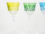 four different colored wine glasses are lined up on a white surface