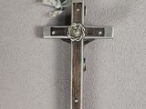 silver and wood cross with a knot on a gray background