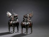 pair of bronze sculptures of two dogs with horns on their heads