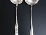 pair of silver spoons on a black surface with a black background