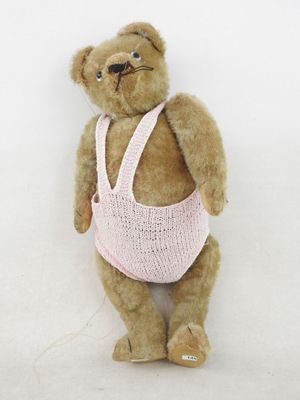 un ours en peluche marron portant un gilet rose tricoté