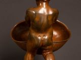 a bronze statue of a child holding a bowl on a wooden base