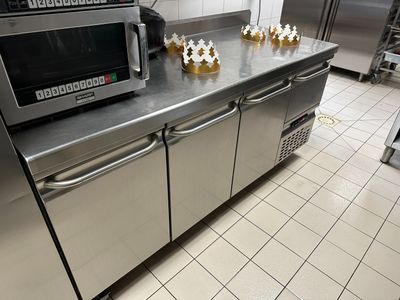 un plan de travail en acier inoxydable dans une cuisine professionnelle, sur lequel est posé un micro-ondes