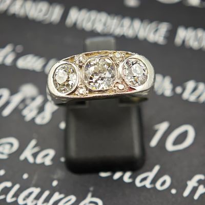 une photo d'une bague en diamant à trois pierres posée sur une surface noire