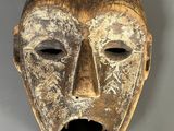 gros plan d'un masque en bois sur une surface blanche