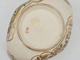 a white plate with gold designs on it on a white surface