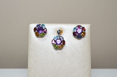 une paire de boucles d'oreilles multicolores et un collier posés sur un présentoir blanc