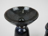 two black vases sitting next to each other on a table