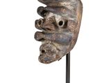 a close up of a wooden mask on a metal stand