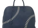 a blue leather bag with white stitching on the side