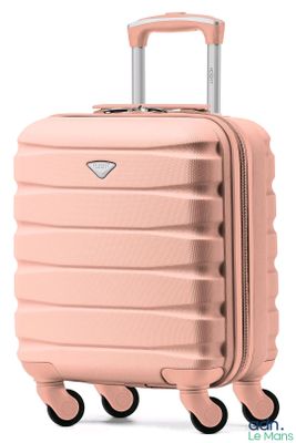 La valise rose repose sur ses roulettes, posée sur une surface blanche.