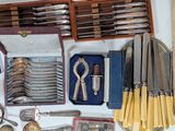 many different types of knives and spoons on the table