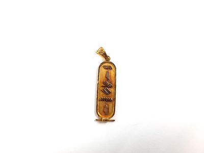 gros plan d'un pendentif en or sur une surface blanche