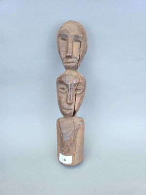 une sculpture en bois représentant un homme, surmontée d'un visage